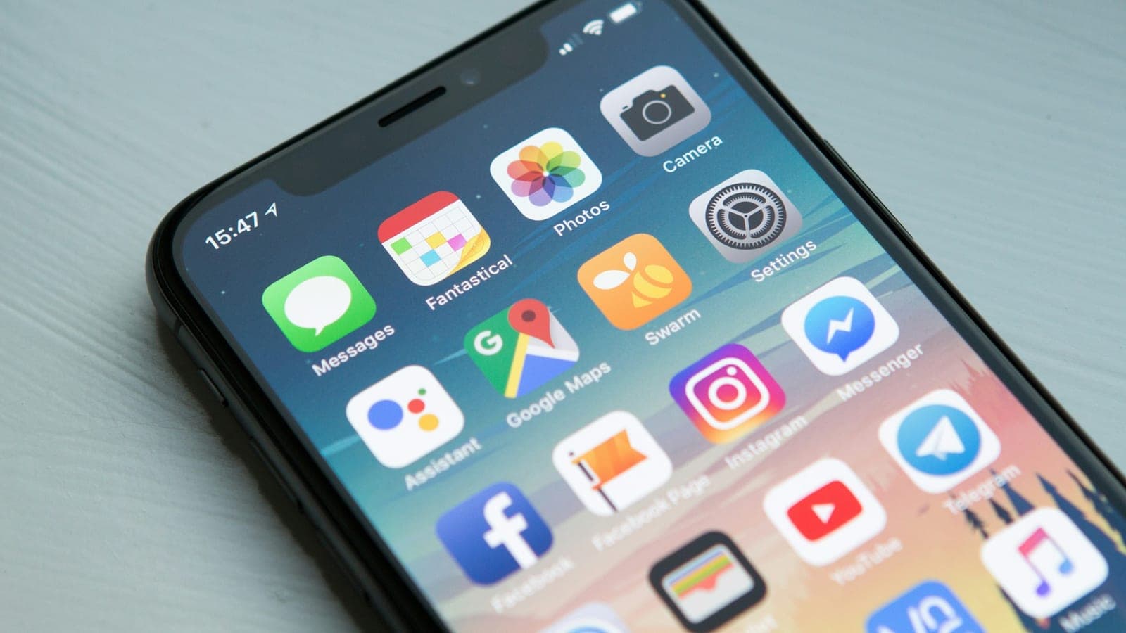 An iPhone X face-up on a white surface, its screen dark and softly reflecting light at the edge